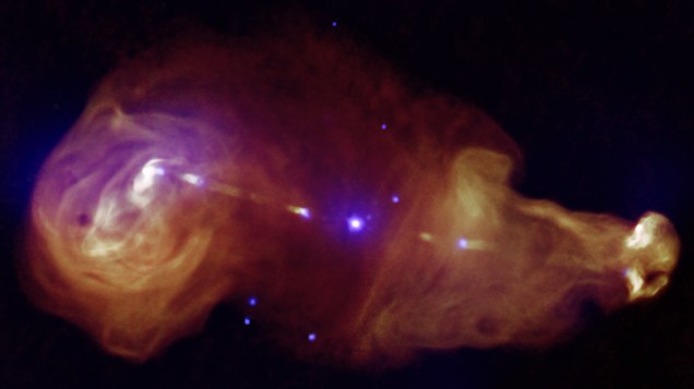 <p>Jatos gerados a partir de buracos negros supermassivos no centro de galáxias podem transportar grandes quantidades de energia. A imagem mostra uma fonte desse tipo de jato, onde a galáxia está ao centro e grandes nuvens de radiação podem ser vistas a partir de observações de raios-x (em roxo), e ondas de radio, obtidas com Very Large Array (em laranja).</p>