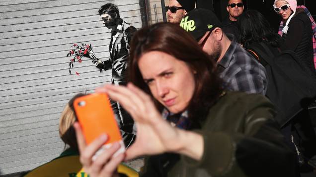 Selfie em frente a pintura do artista britânico Banksy na entrada principal Hustler Club Larry Flint, em Nova York