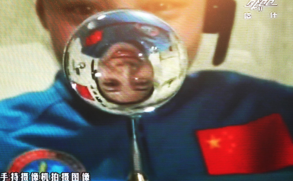 Astronauta Wang Yaping é refletida em uma gota de água flutuando no módulo espacial Tiangong-1 durante aula no espaço