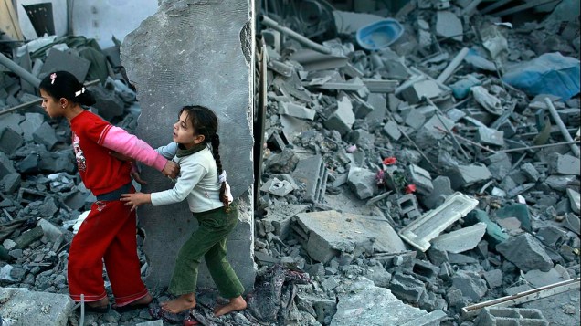 Meninas andam sobre escombros na Faixa de Gaza