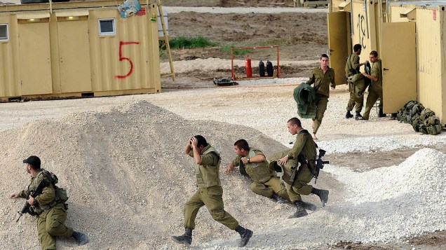 Soldados israelenses correm para se enconder após alerta de sirene, em Ashdod