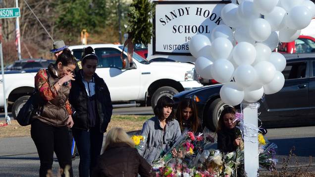 Moradores da cidade de Newtown prestam homenagens às vítimas do tiroteio, em frente a escola Sandy Hook