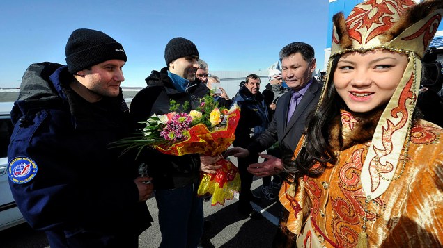 Os cosmonautas russos Oleg Novitskiy e Evgeny Tarelkin da Estação Espacial Internacional recebem flores após aterissagem no Cazaquistão