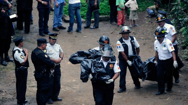 Bombeiros carregam os corpos de sete pessoas da mesma família que foram assassinadas em Las Escobas, Guatemala