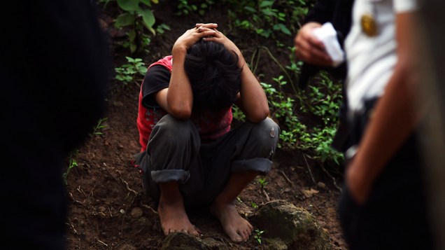 Criança que conseguiu escapar de um ataque contra sua família é protegida por policiais no vilarejo de Las Escobas, nos arredores da Cidade da Guatemala, onde o crime ocorreu