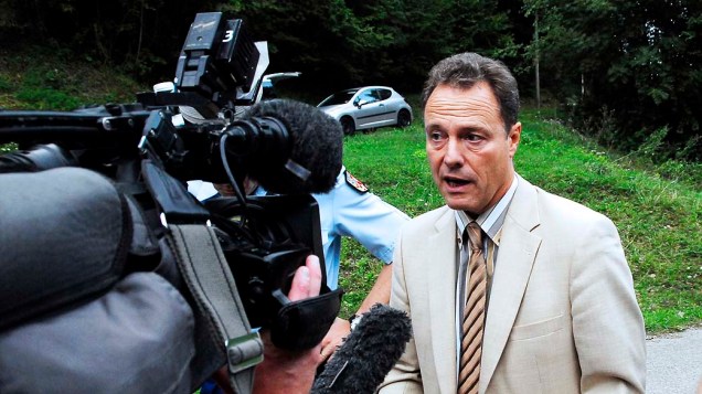 Promotor do Annecy responde a perguntas dos jornalistas na estrada que leva para a cena do crime