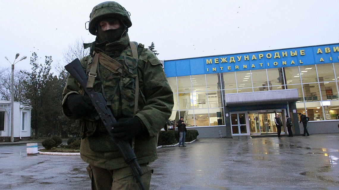Homem armado patrulha estacionamento de aeroporto na Crimeia, no sul da Ucrânia, após invasão de grupo pró-Rússia