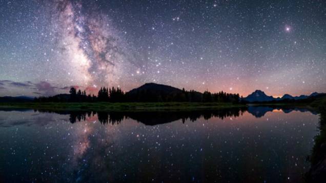 <p>Via Láctea refletida no rio Snake, no Parque Nacional de Grand Teton, nos Estados Unidos</p>