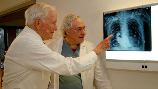Dento A. Cooley (esq.), responsável pelo primeiro transplante com coração artificial do mundo, e Bud Frazier observam raio-X do tórax do paciente Craig Lewis