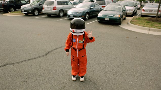 <p>Criança com capacete de astronauta durante o transporte do ônibus espacial Discovery</p>