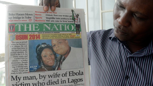 Homem segura jornal com imagem do diplomata liberiano Patrick Sawyer, morto pelo vírus ebola na cidade de Lagos, na Nigéria