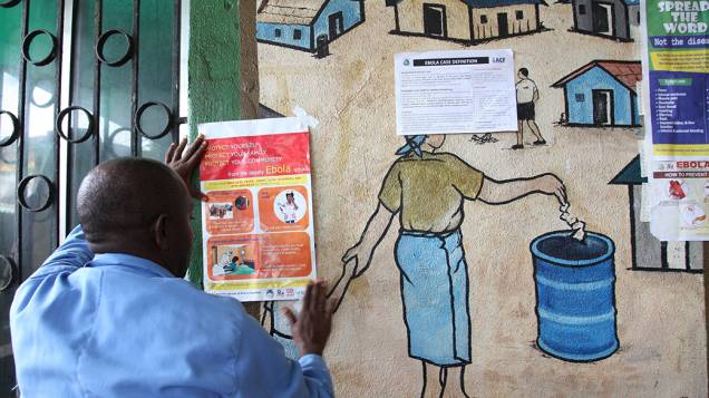 Homem cola informativo sobre o vírus ebola, na Libéria