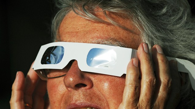 Turista observa eclipse total do Sol na cidade de Palm Cove, na Austrália