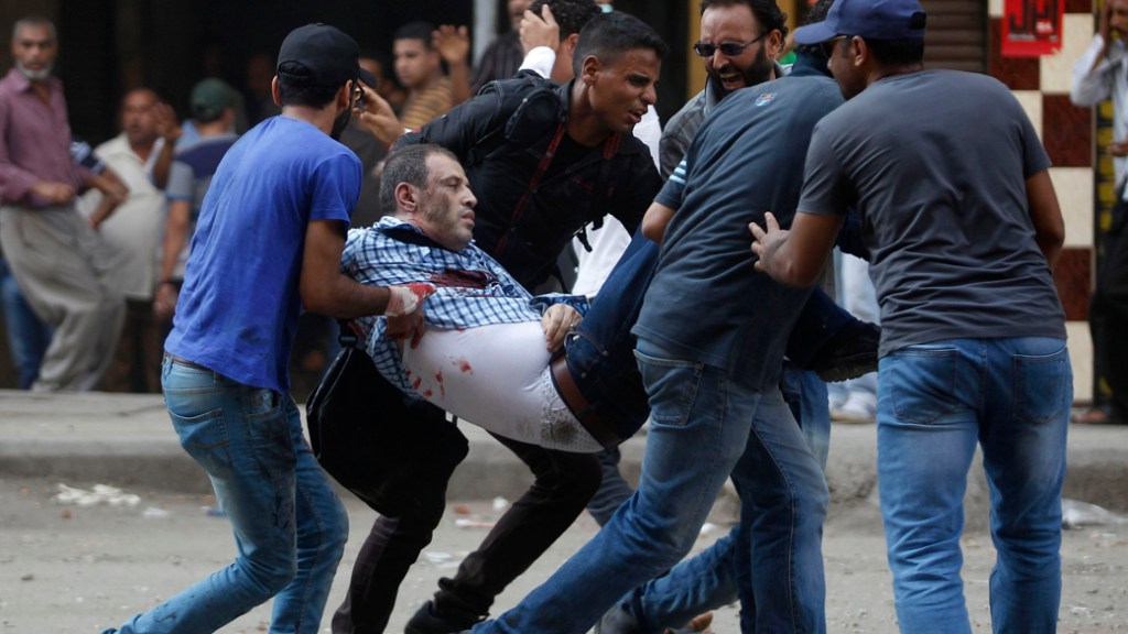 Partidários do presidente deposto egípcio Mohamed Mursi socorrem um manifestante ferido durante confrontos na Praça Ramsés, no Cairo