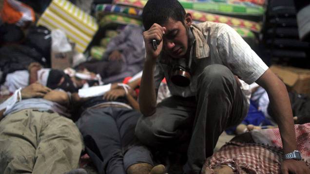 Um homem chora em meio aos corpos dispostos em um necrotério depois que as forças de segurança egípcias atacaram dois acampamentos onde partidários do presidente deposto Mohamed Mursi estavam acampados no Cairo, nesta quarta feira (14/08/2013)