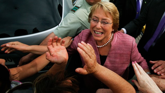 Michelle Bachelet cumprimenta funcionários da seção eleitoral onde votou em Santiago, neste domingo (17)