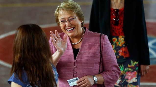 Michelle Bachelet cumprimenta funcionários da seção eleitoral onde votou em Santiago, neste domingo (17)