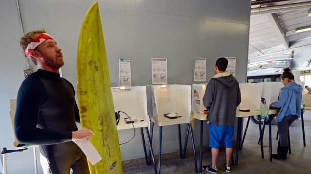Eleitor vota com uma prancha de surfe e vestindo uma roupa de lycra em Venice Beach, na Califórnia