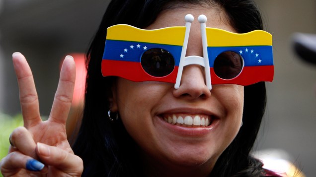 Cidadã venezuelana que vive no México posa usando óculos com as cores da bandeira do seu país próximo ao consulado da Venezuela no México, durante as eleições presidenciais