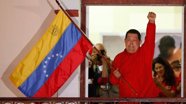 Hugo Chávez segura a bandeira venezuelana ao falar para apoiadores em Caracas depois de ser reeleito em outubro de 2012