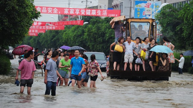 Pessoas caminham por região alagada na próvíncia de Sichuan. Chuva forte vem atingindo a região e provocando deslizamentos de terra