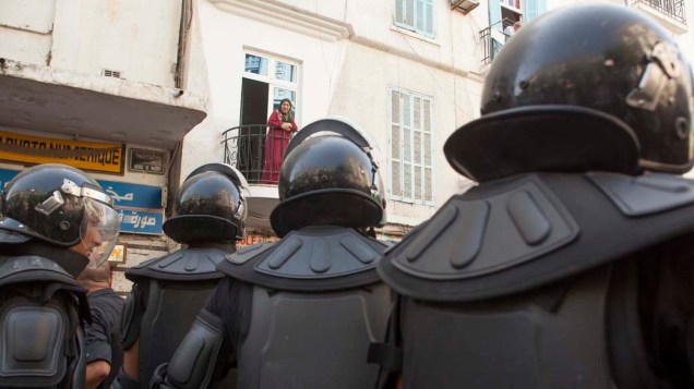 Uma moradora de Túnis observa a tropa de choque da polícia, mobilizada para enfrentar manifestantes islamistas após a reza de sexta-feira