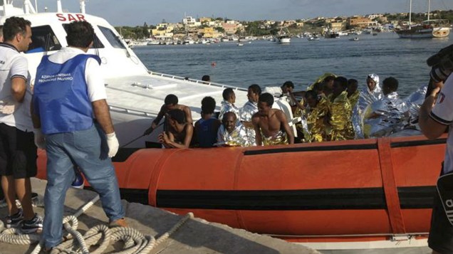 Equipes de resgate levam sobreviventes de naufrágio para a costa da Ilha de Lampedusa, na Itália