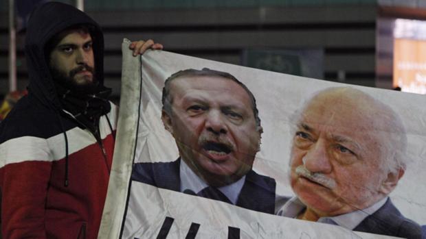 Manifestante segura faixa com imagens do primeiro-ministro Recep Tayyip Erdogan e do clérigo Fetullah Gülen (dir), durante protesto contra o governo turco em Istanbul