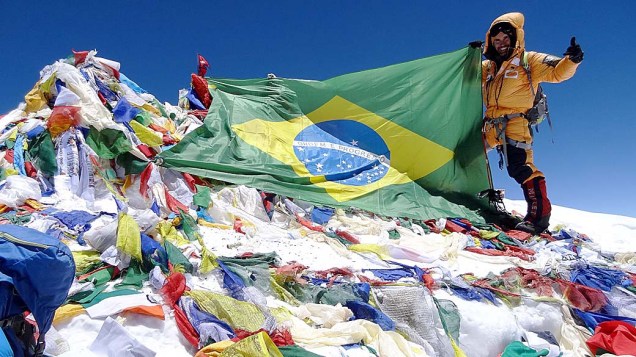 O alpinista Rodrigo Raineri segura a bandeira do Brasil no topo do Everest