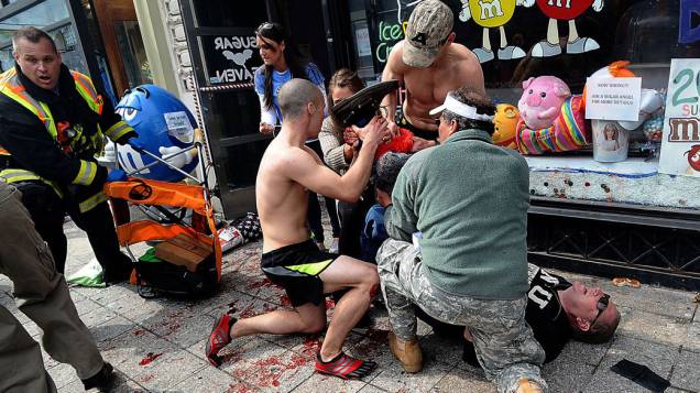 Espectadores atendem a um homem ferido após sequência de explosões durante a Maratona de Boston, em Massachusetts