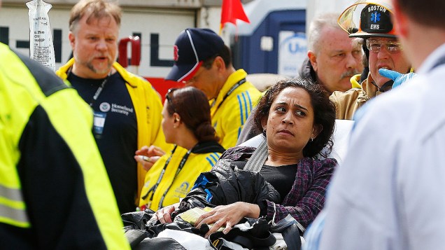 Mulher é levada até uma ambulância por equipes de resgate, após duas explosões na maratona de Boston