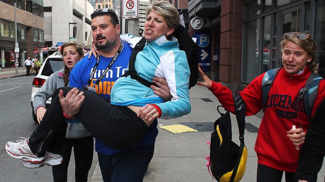 Mulher é carregada por um homem, após duas explosões na maratona de Boston