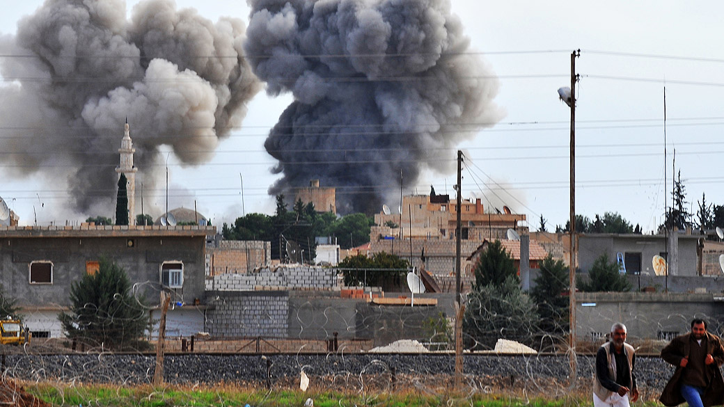 Pessoas correm após bombardeio aéreo sírio na cidade fronteiriça Ras al-Ain, na Turquia