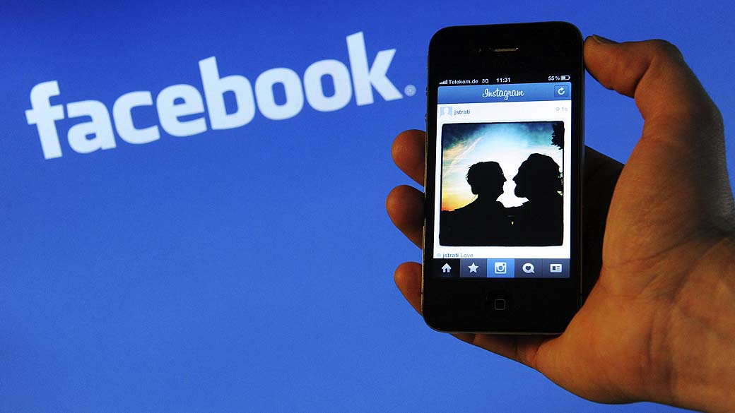 IPhone com Instagram aberto ao lado do logo do Facebook