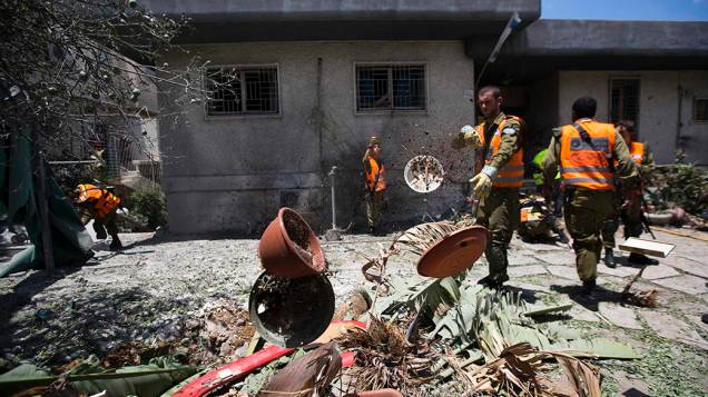 Em Israel, soldados andam em meio aos escombros de uma casa destruída por um foguete disparado por militantes palestinos na Faixa de Gaza, em 15/07/2014