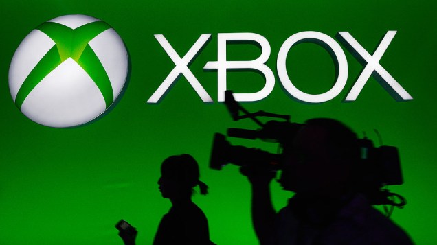 Equipe de TV passa diante de um painel do Xbox durante a E3 2013, em Los Angeles