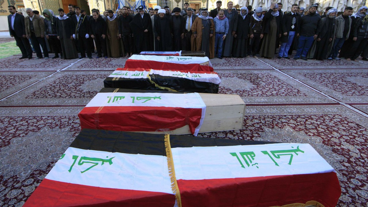 Fiéis rezam em frente aos caixões de membros das forças de segurança mortos em Ramadi, no Iraque