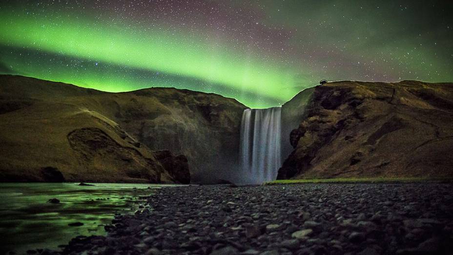 <p>Foto capta uma aurora boral sobre a cachoeira Skógafoss, uma das maiores queda dágua da Islândia</p>