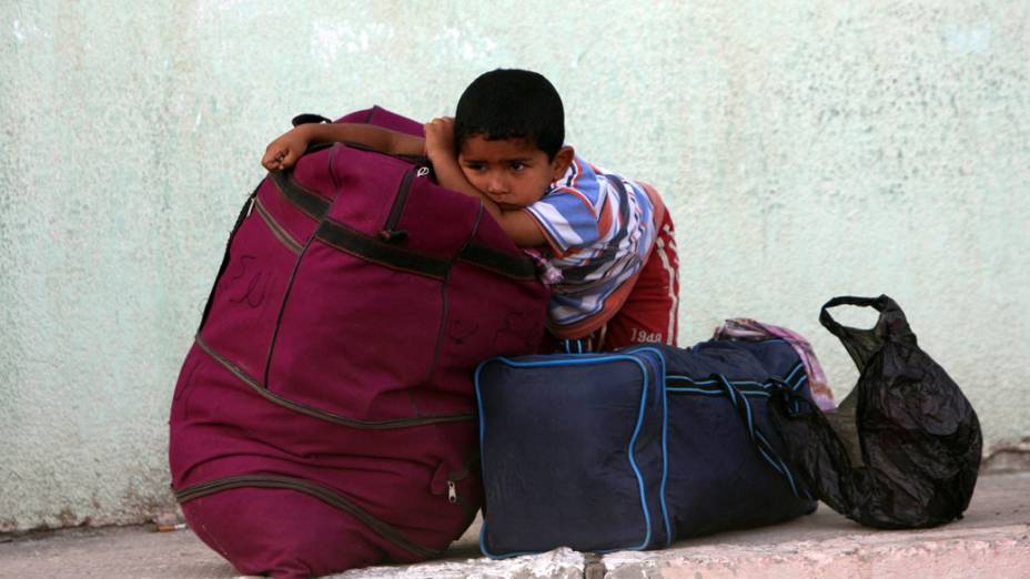 Garoto palestino aguarda com a família para atravessar a fronteira com o Egito, na cidade de Rafah, em Gaza