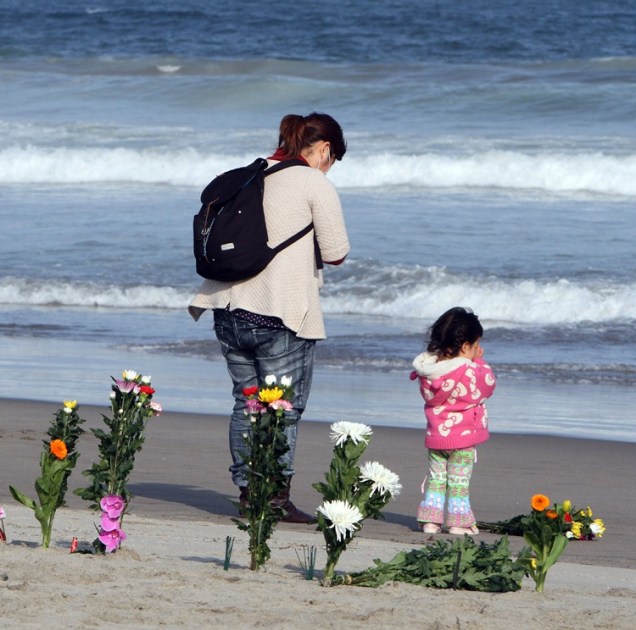 <p>Uma menina e sua mãe rezam na praia de Arahama pelas vítimas do terremoto seguido por tsunami que devastou o Japão há um ano</p>