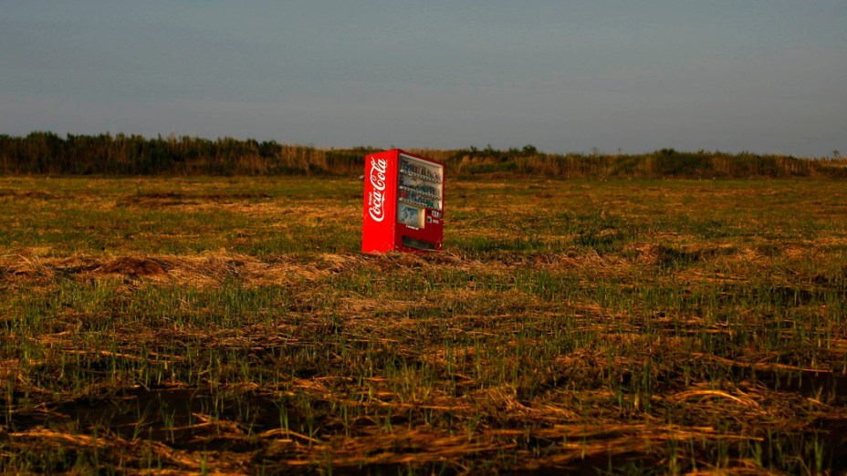 A máquina de venda de refrigerantes abandonada em uma plantação de arroz