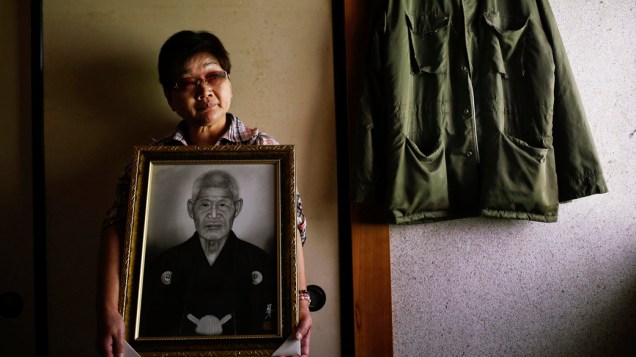 Mieko Okubo, de 59 anos, posa com um retrato de seu pai que cometeu suicídio aos 102 anos de idade, após o desastre nuclear na usina Daiichi
