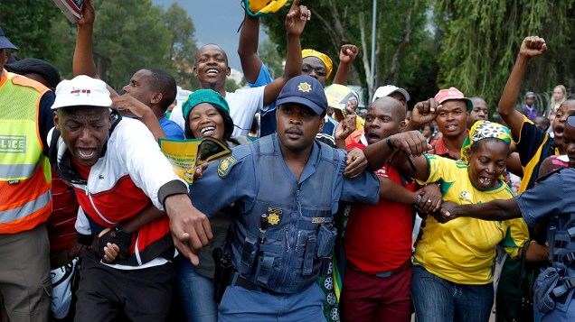 Multidão se aglomera atrás de um cordão policial, após serem impedidos de entrar no velório de Nelson Mandela, em Pretória