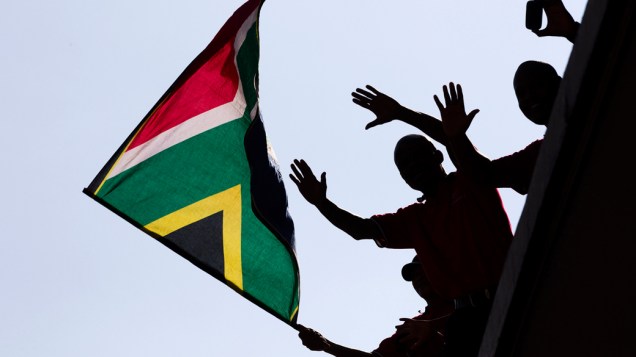 Homens com a bandeira da África do Sul durante cortejo fúnebre, em Pretória