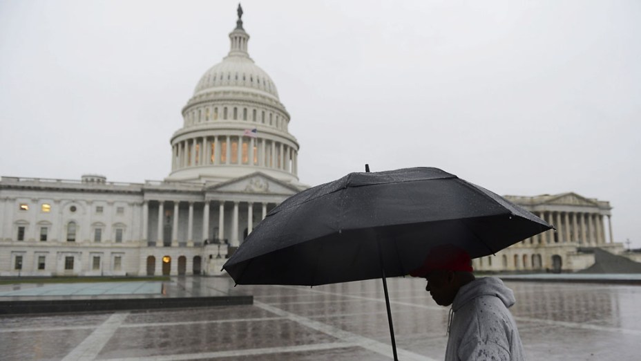 Homem se protege com guarda-chuva em frente ao Capitólio em Washington durante aproximação do furacão Sandy