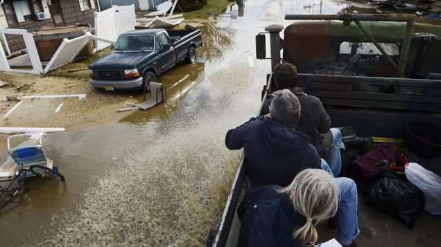 Pessoas resgatadas por veículos do exército, observam os danos causados pela tempestade Sandy em Nova Jersey