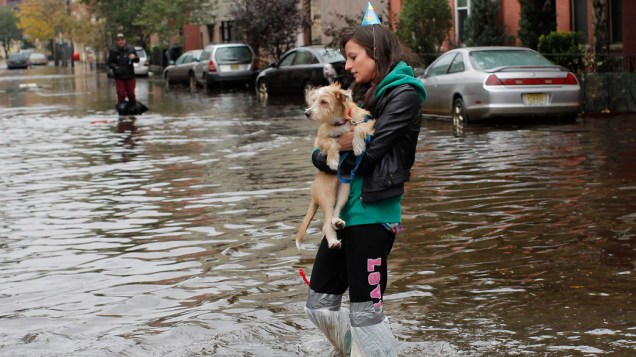 Mulher carrega seu cachorro em meio à enchente provocada pela tempestade Sandy em Hoboken, Nova Jersey