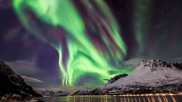 <p>Aurora Boreal sobre um fiorde, na Noruega. As cores são produzidas a diferentes altitudes por diversos gases atmosféricos, sendo o azul emitido pelo nitrogênio e verde pelo oxigênio. Vermelho pode ser produzido por ambos, enquanto roxo, rosa e amarelo ocorrem quando há mistura de cores</p>