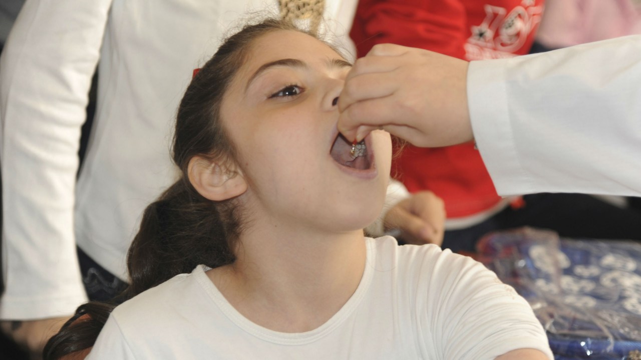 Garota síria recebe vacina contra pólio em uma escola em Damasco, na Síria
