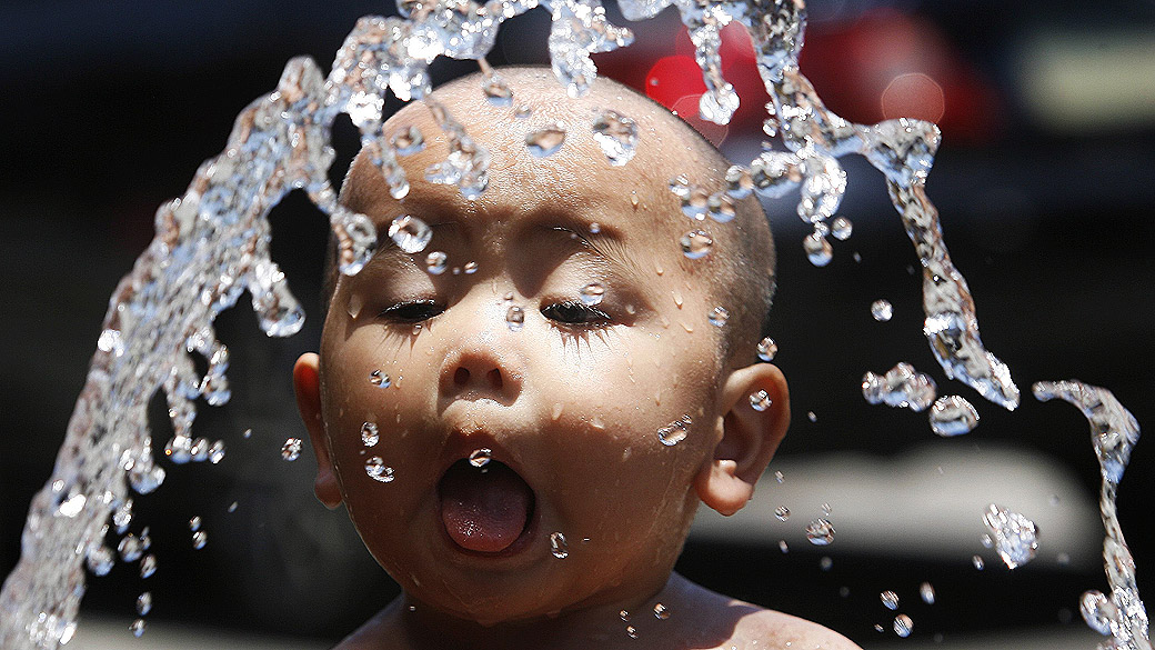 Menino se refresca com água de mangueira em Manila, nas Filipinas